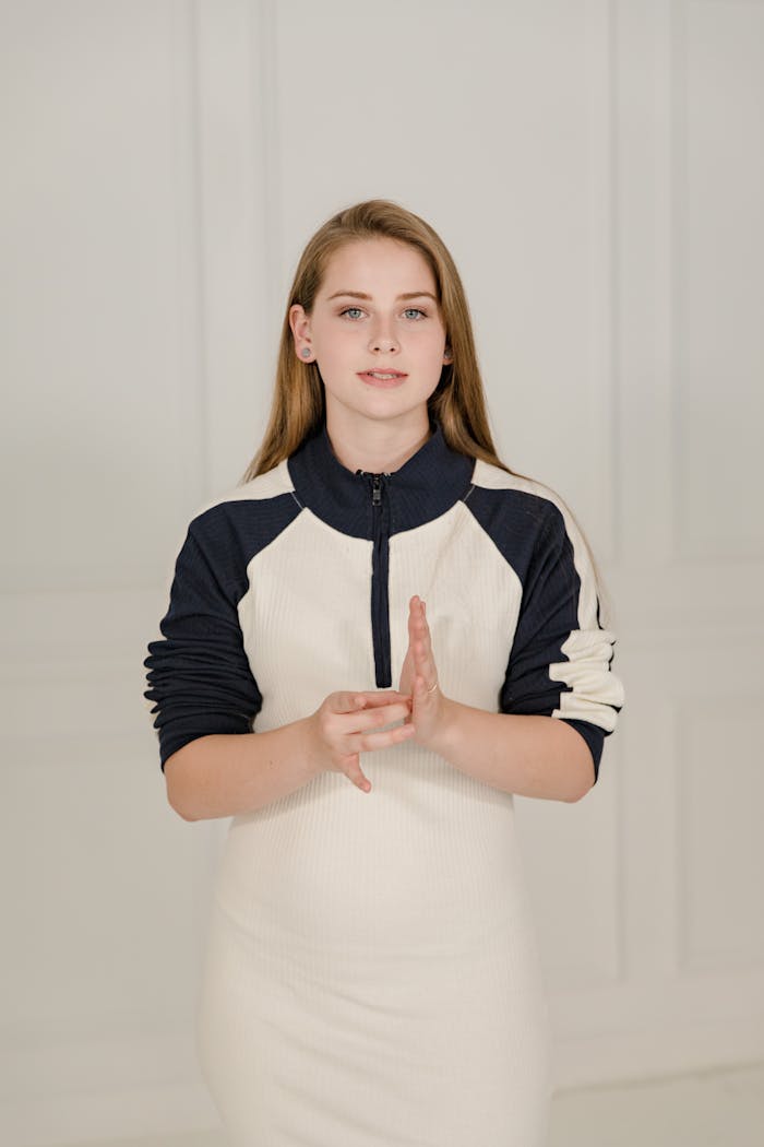 A woman using sign language to communicate, standing indoors, signifying inclusivity and communication.